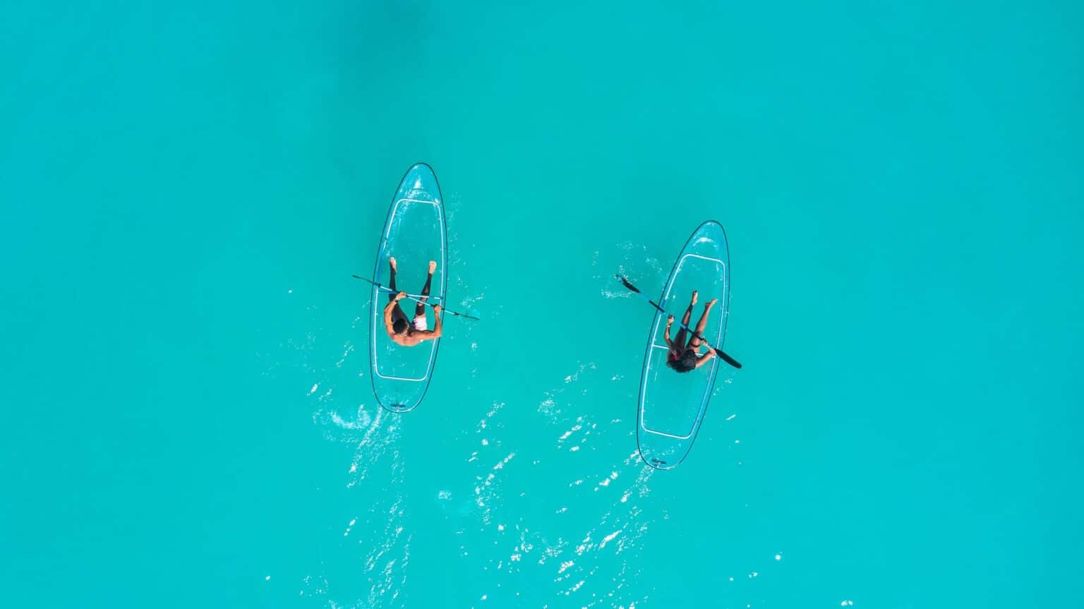 2 people kayaking in transparant kayak clear water
