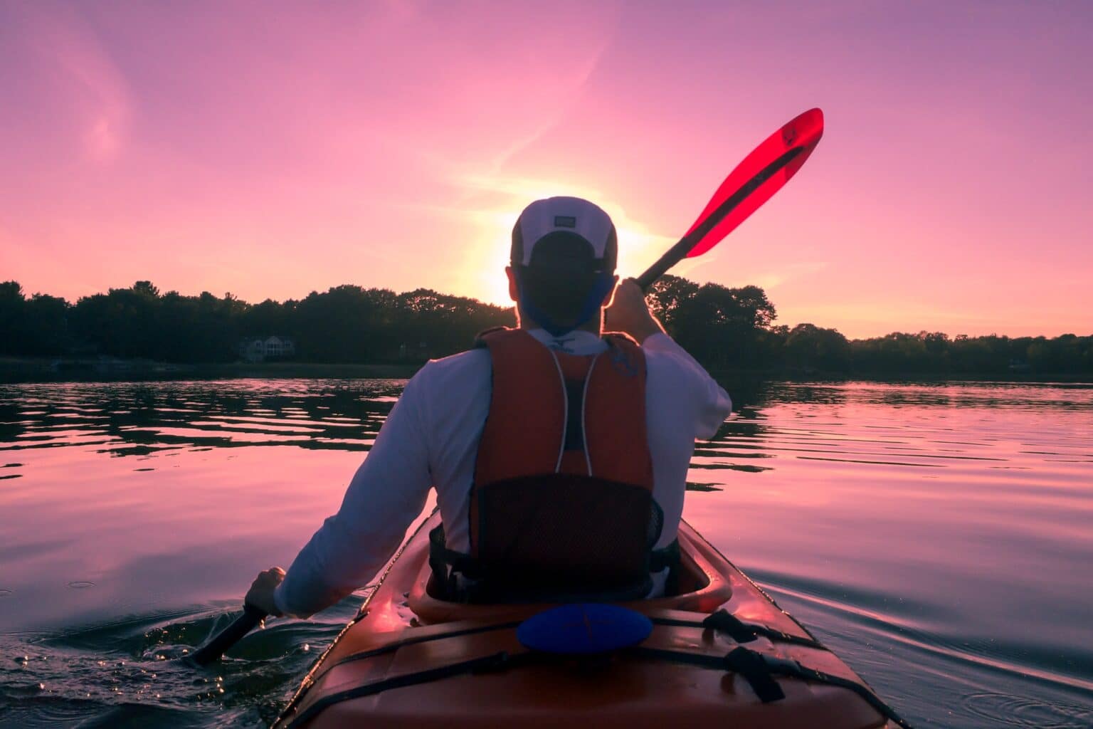 man kayaking in a river with beautiful sunset