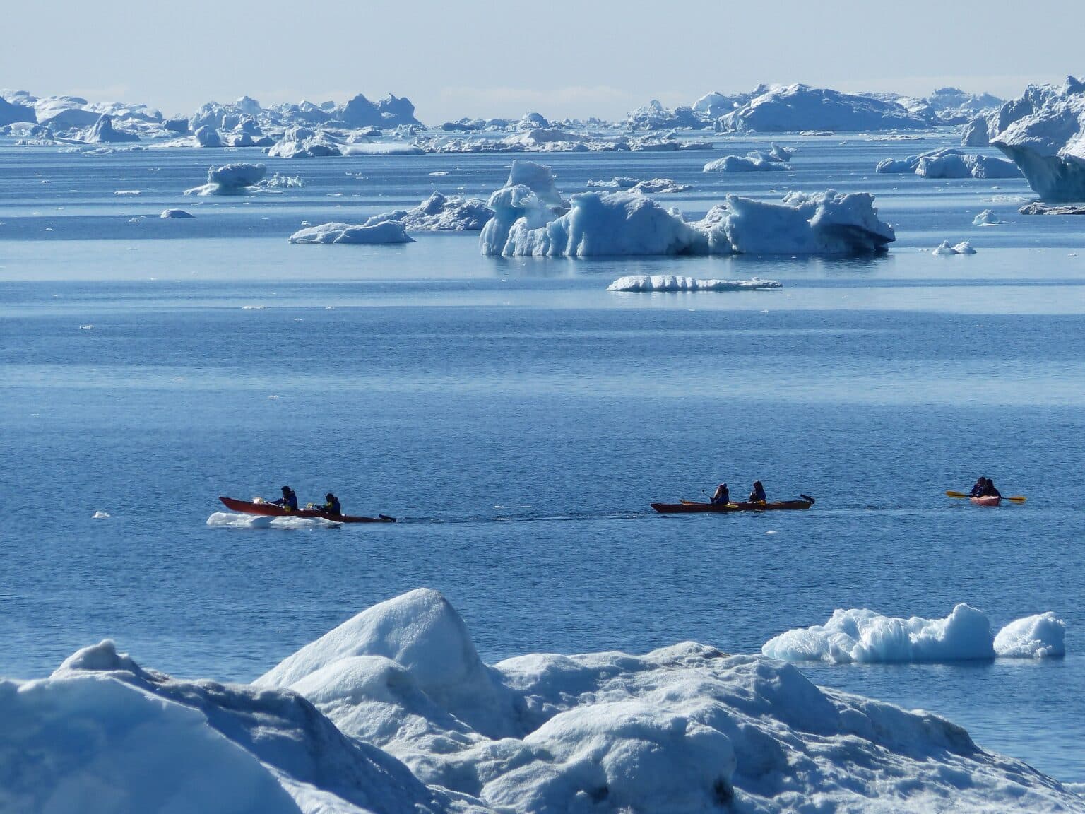 a group of people Kayaking south of Oqaatsut winter landscape