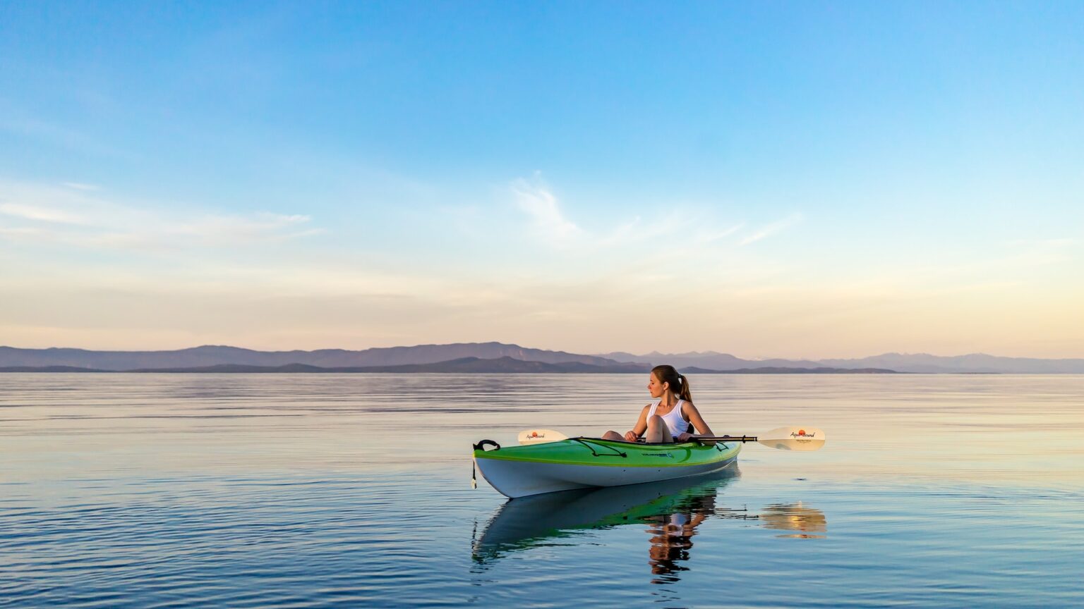 girl relaxing in kayak on tranquil sea enjoing sunset