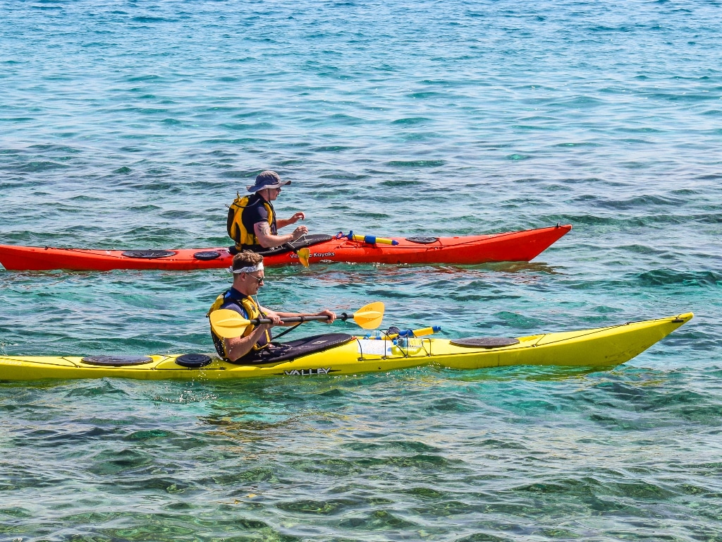 Two kayakers sea kayaking in yellow and red kayaks
