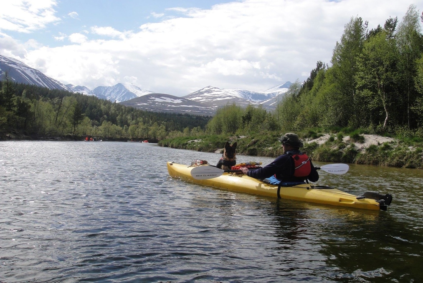 men kayaking with dog on river background icy mountains