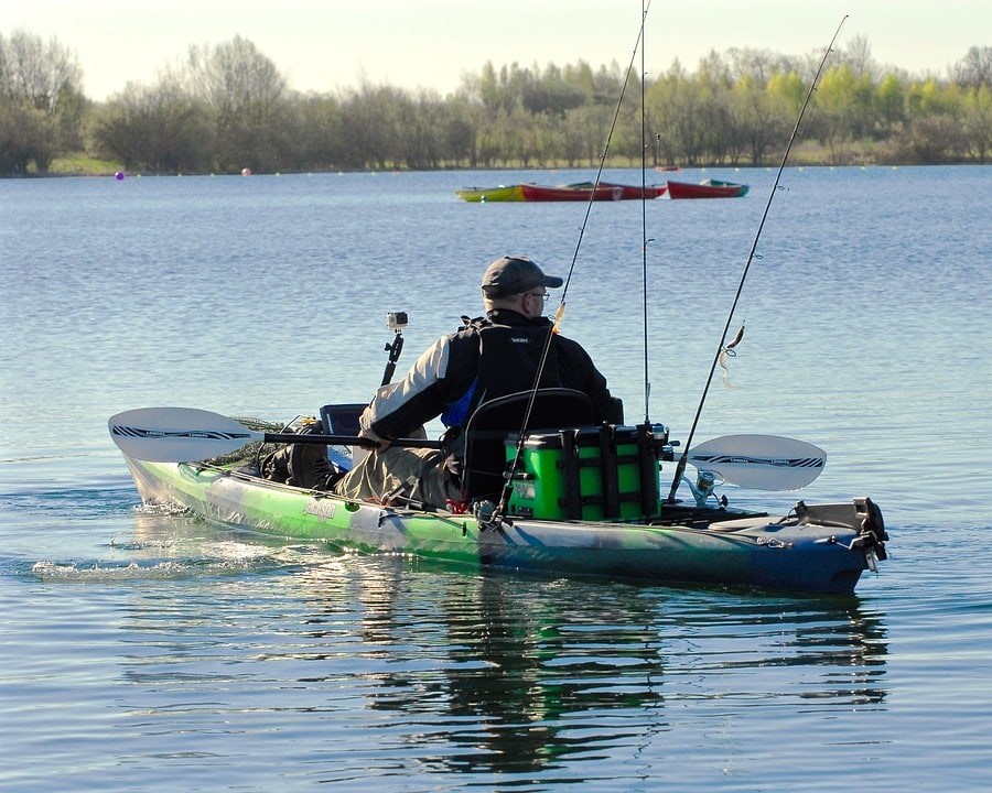 Men fishing from a specialized fishing kayak on a serene lake