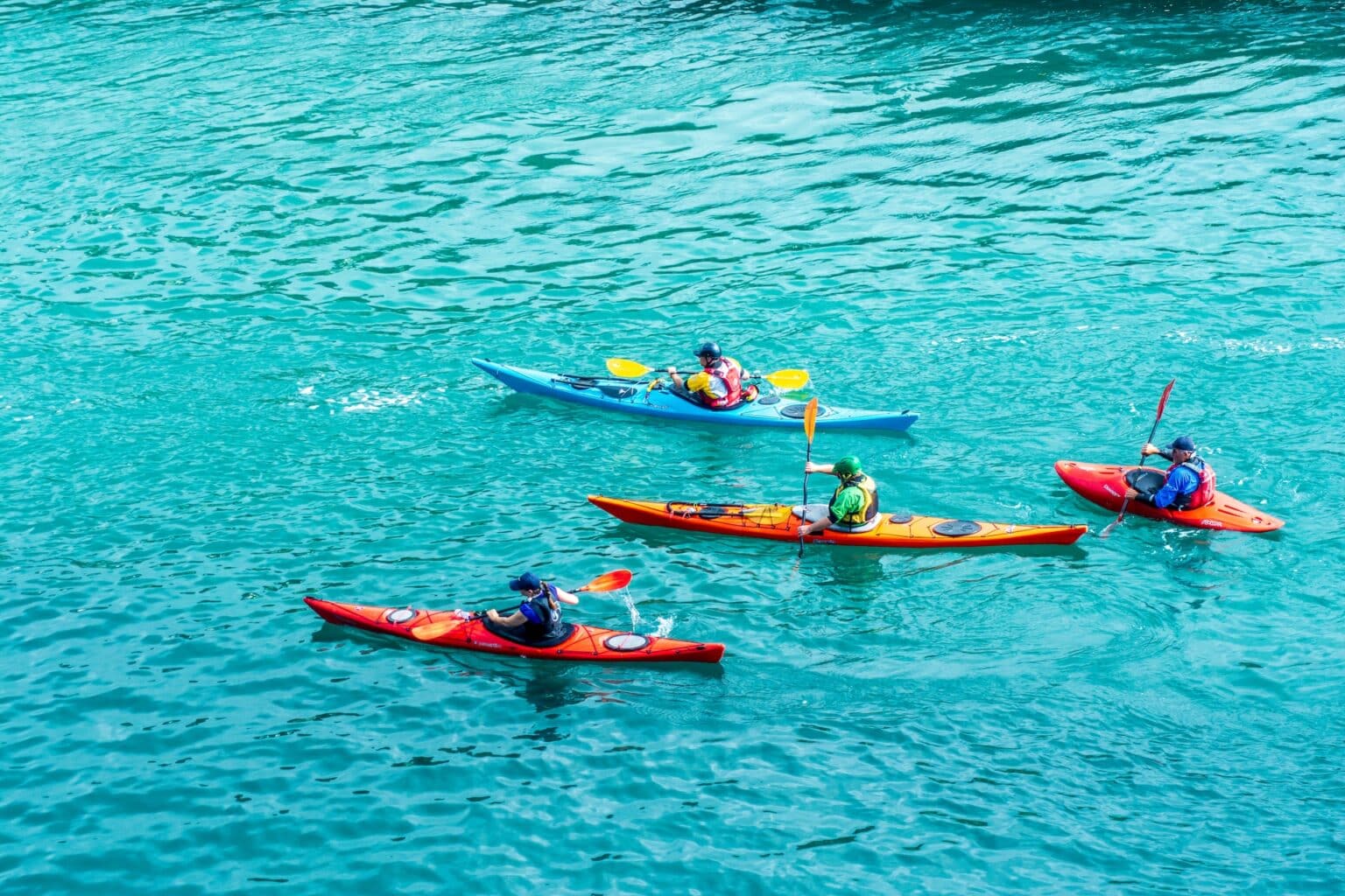 people sea kayaking with different sized kayaks
