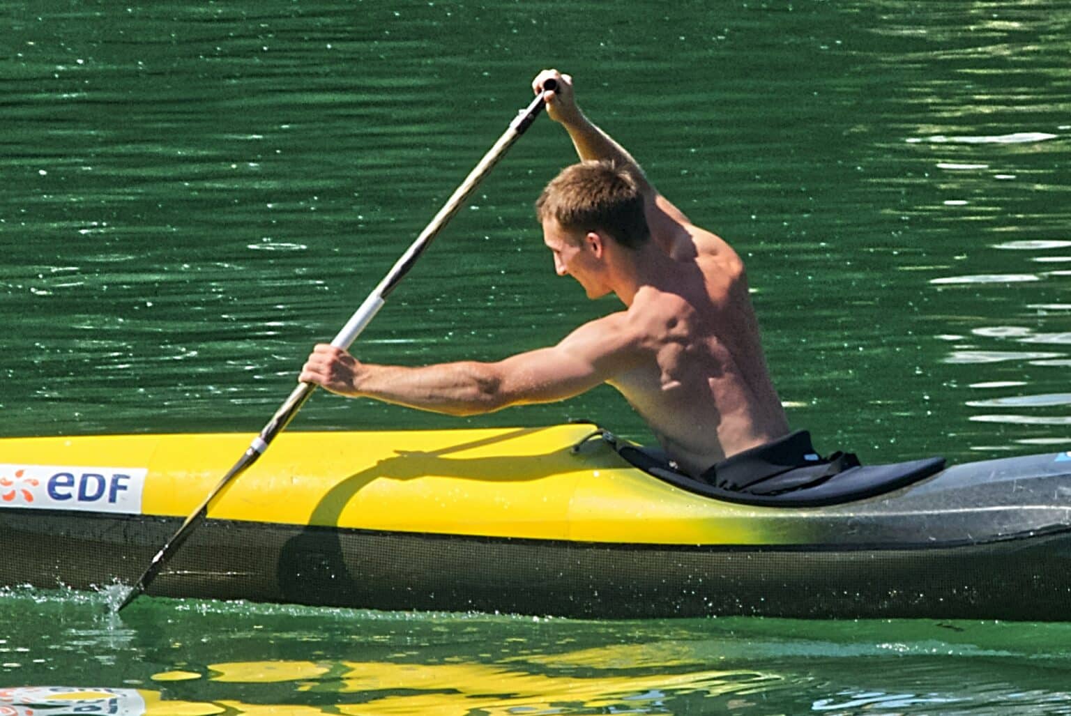 ripped muscular guy paddling intensively in lake